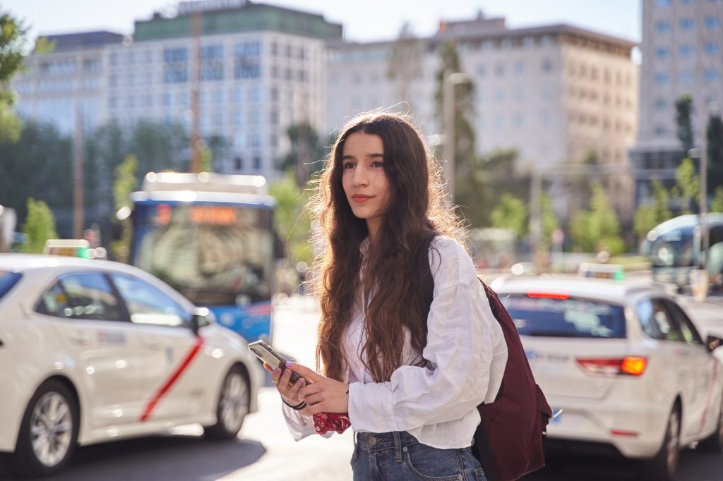 woman waiting for ride share as taxi cabs drive by in Spain